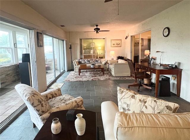 living room featuring ceiling fan and a textured ceiling