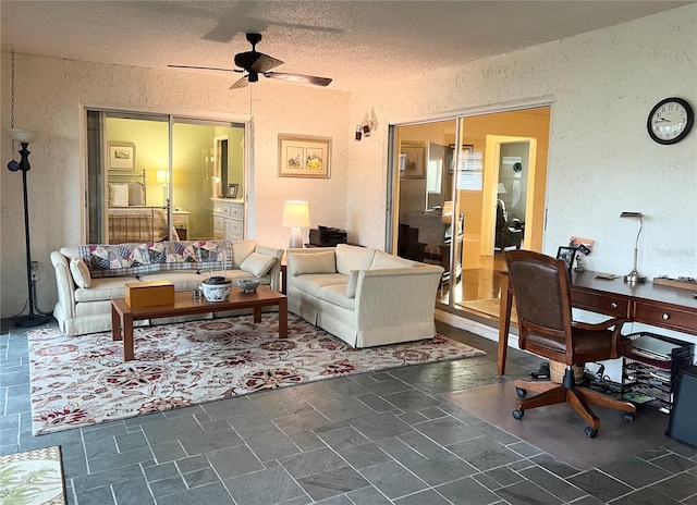 living room featuring ceiling fan and a textured ceiling