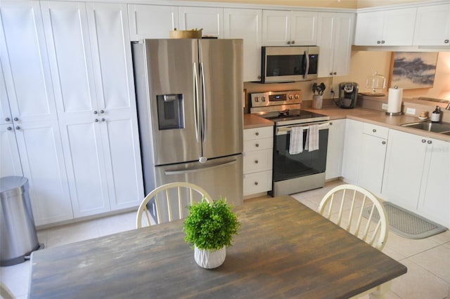 kitchen with white cabinetry, light tile patterned floors, sink, and appliances with stainless steel finishes