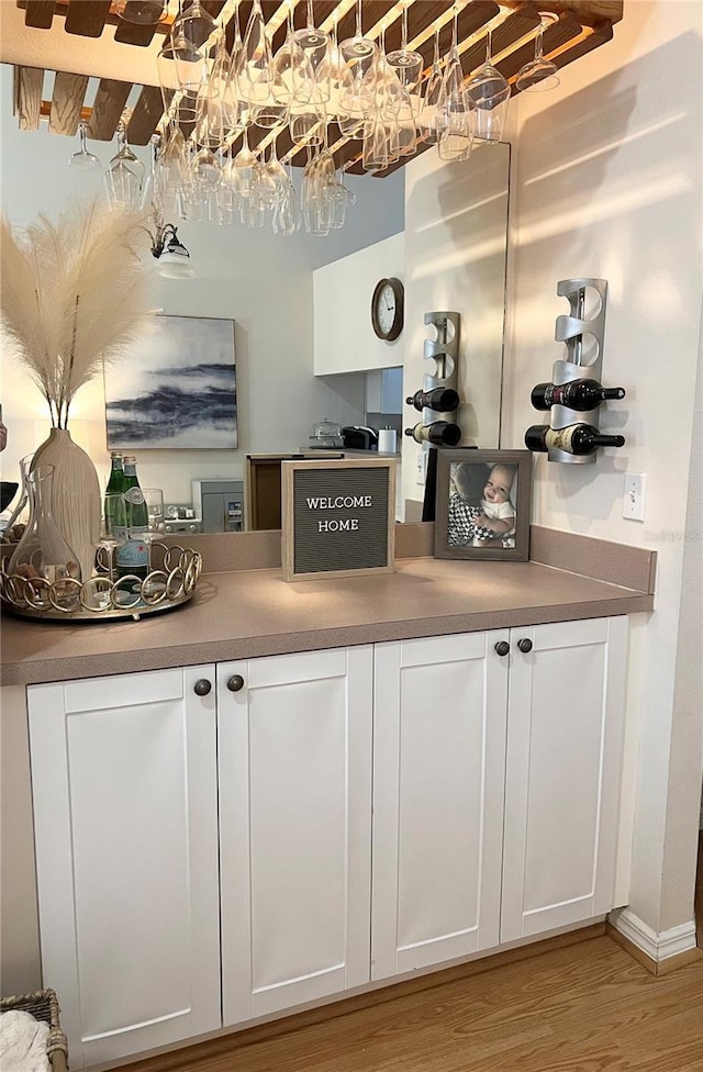 bar with light hardwood / wood-style flooring and white cabinets