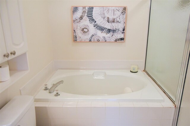 bathroom with tiled tub and toilet