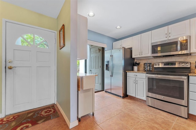 kitchen featuring white cabinets, stainless steel appliances, light tile patterned floors, and decorative backsplash