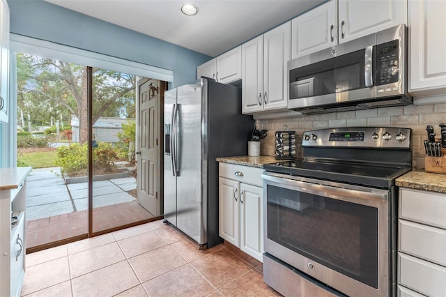 kitchen featuring tasteful backsplash, white cabinetry, light tile patterned floors, light stone countertops, and stainless steel appliances