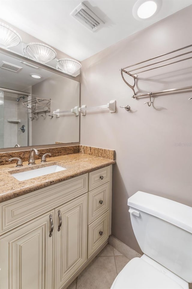 bathroom with an enclosed shower, vanity, toilet, and tile patterned flooring