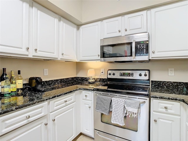 kitchen with white cabinets, stainless steel appliances, and dark stone counters