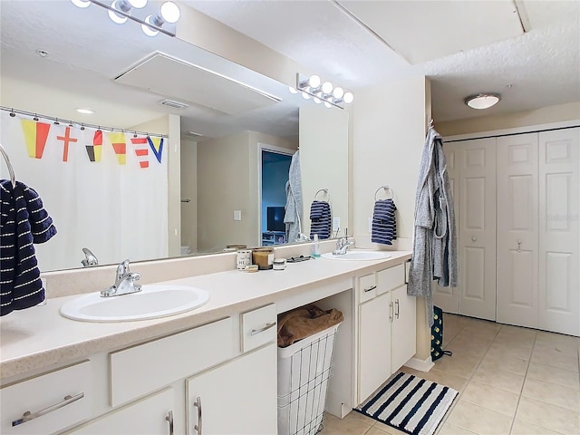 bathroom with a textured ceiling, tile patterned flooring, and vanity