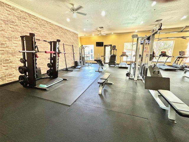 exercise room with ceiling fan, a wealth of natural light, brick wall, and a textured ceiling