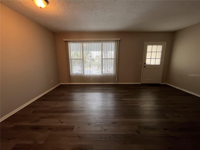 spare room featuring dark wood-type flooring and a textured ceiling