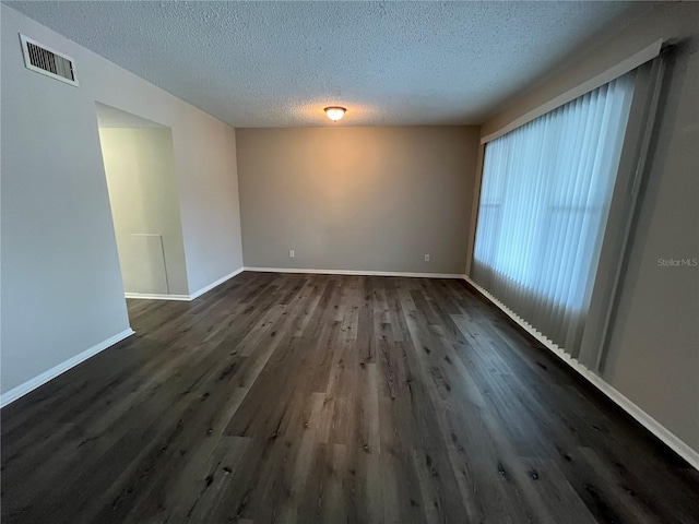 empty room featuring dark hardwood / wood-style floors and a textured ceiling