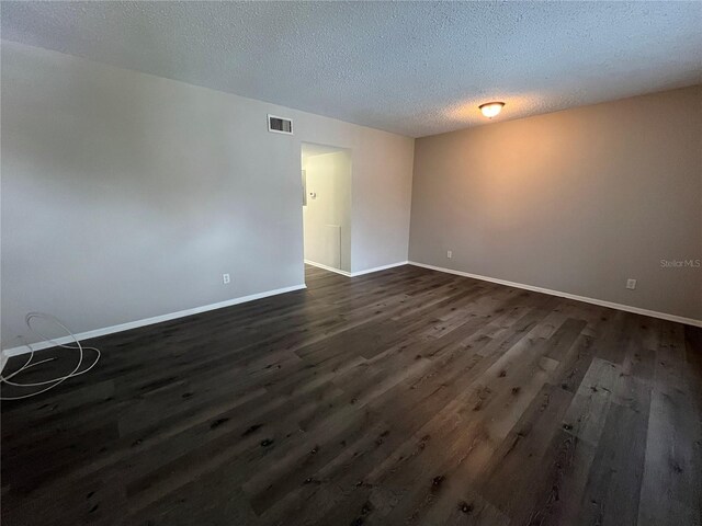 unfurnished room featuring a textured ceiling and dark hardwood / wood-style floors