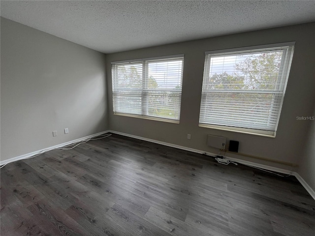 empty room featuring a textured ceiling and dark hardwood / wood-style flooring