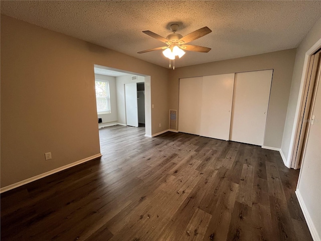 unfurnished bedroom with ceiling fan, a textured ceiling, dark hardwood / wood-style flooring, and a closet