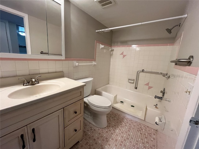 full bathroom featuring toilet, tiled shower / bath combo, tile walls, tile patterned floors, and vanity