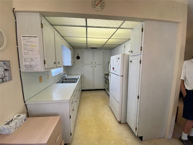 kitchen featuring sink, white refrigerator, white cabinets, and a drop ceiling