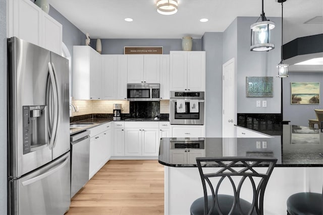 kitchen with pendant lighting, sink, appliances with stainless steel finishes, white cabinetry, and light hardwood / wood-style floors