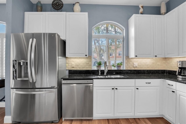 kitchen with dark stone countertops, sink, white cabinetry, and stainless steel appliances