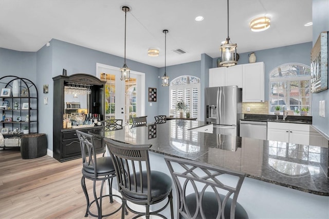 kitchen with dark stone countertops, backsplash, white cabinets, and appliances with stainless steel finishes