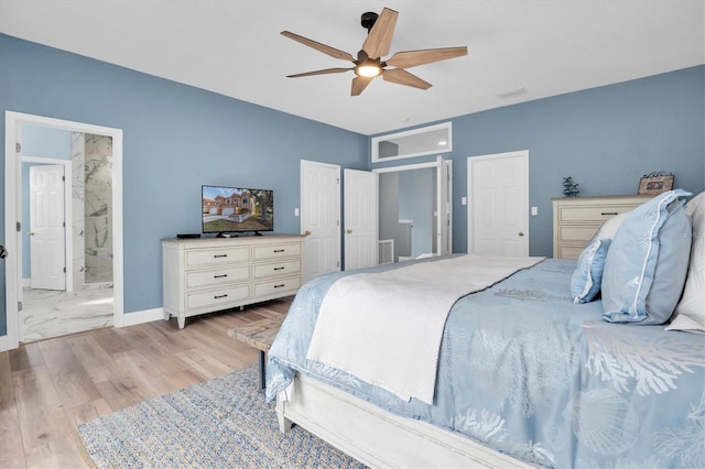 bedroom featuring ceiling fan, ensuite bath, and light wood-type flooring