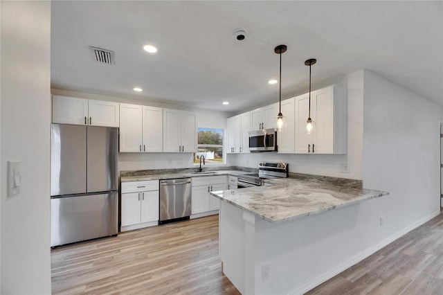 kitchen featuring appliances with stainless steel finishes, white cabinetry, sink, kitchen peninsula, and light hardwood / wood-style flooring