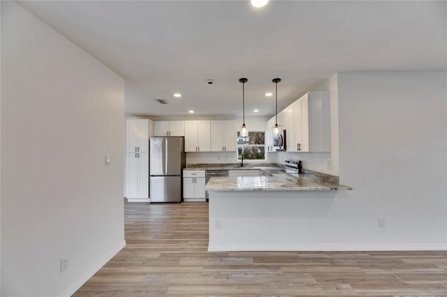 kitchen featuring white cabinets, appliances with stainless steel finishes, sink, hanging light fixtures, and kitchen peninsula