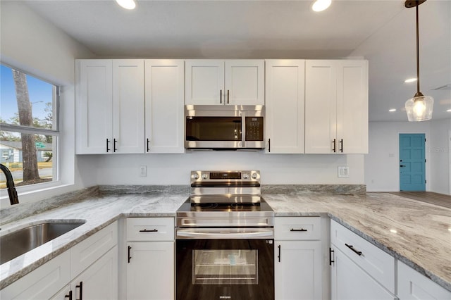 kitchen with sink, white cabinets, decorative light fixtures, and appliances with stainless steel finishes