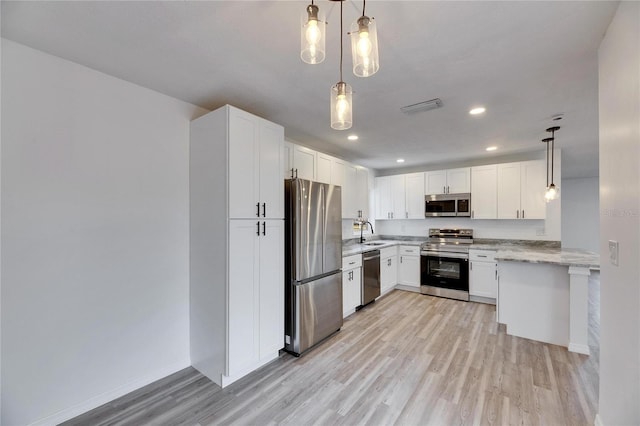 kitchen with decorative light fixtures, light hardwood / wood-style floors, white cabinetry, and appliances with stainless steel finishes