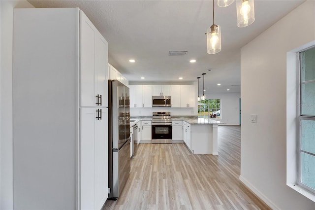 kitchen featuring white cabinetry, stainless steel appliances, light hardwood / wood-style floors, hanging light fixtures, and kitchen peninsula