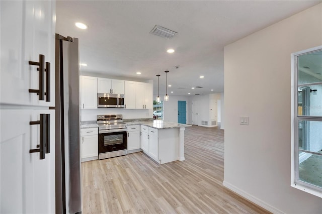 kitchen with decorative light fixtures, kitchen peninsula, white cabinets, and stainless steel appliances