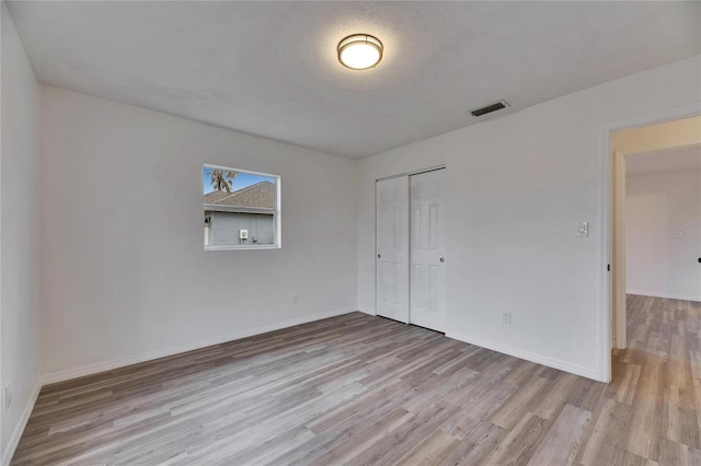 unfurnished room with light hardwood / wood-style floors and a textured ceiling