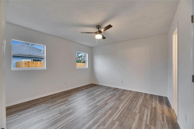 empty room with light wood-type flooring, ceiling fan, and a textured ceiling