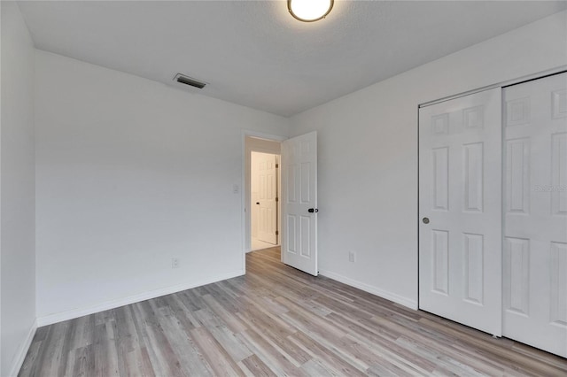 unfurnished bedroom with a closet, light wood-type flooring, and a textured ceiling