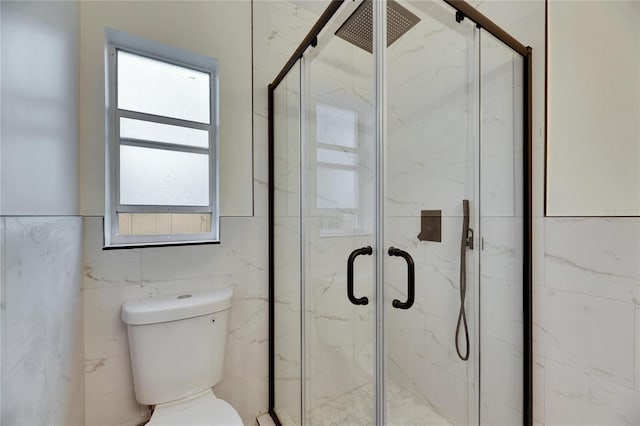 bathroom featuring a shower with shower door and toilet