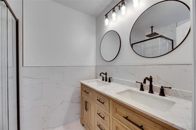 bathroom with vanity, a shower with shower door, and tile walls