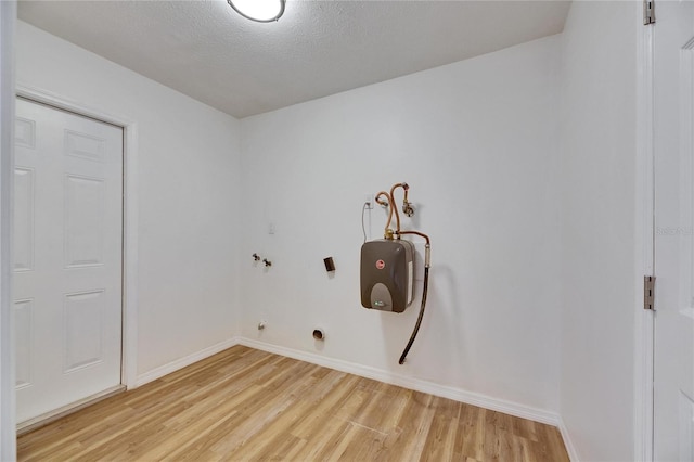 laundry room with a textured ceiling and light hardwood / wood-style flooring