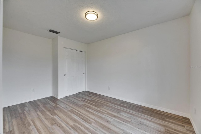 spare room with light hardwood / wood-style floors and a textured ceiling