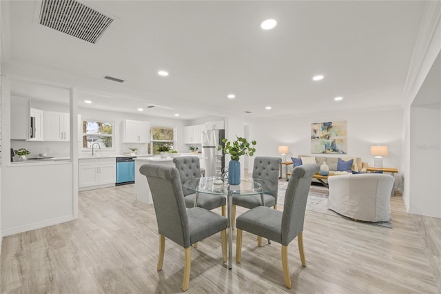 dining space featuring crown molding, light hardwood / wood-style floors, and sink