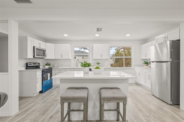 kitchen featuring white cabinetry, stainless steel appliances, and a center island