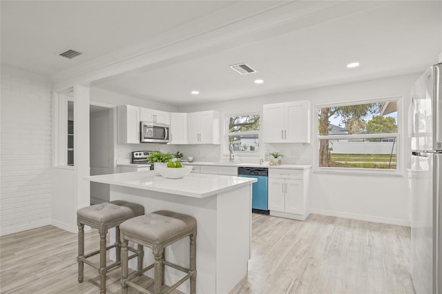 kitchen with white cabinetry, light hardwood / wood-style flooring, stainless steel appliances, and a center island