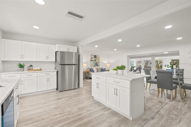 kitchen featuring beam ceiling, appliances with stainless steel finishes, white cabinets, and light hardwood / wood-style floors