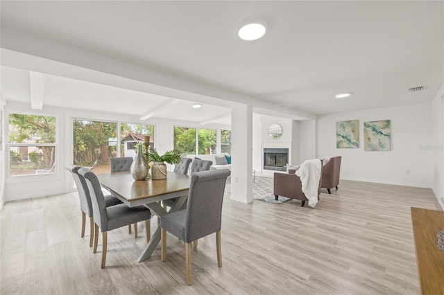 dining room featuring beam ceiling and light hardwood / wood-style flooring