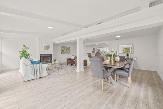 dining space featuring beam ceiling and light hardwood / wood-style flooring