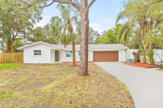 ranch-style home with a garage, a front yard, and central air condition unit