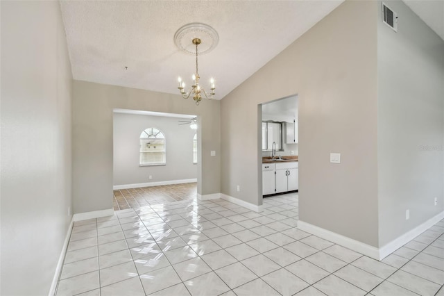 empty room with sink, ceiling fan with notable chandelier, vaulted ceiling, and light tile patterned flooring