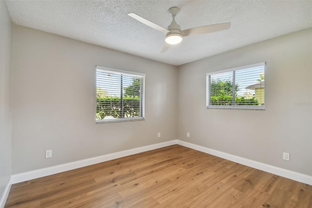 empty room featuring ceiling fan, a healthy amount of sunlight, a textured ceiling, and light wood-type flooring