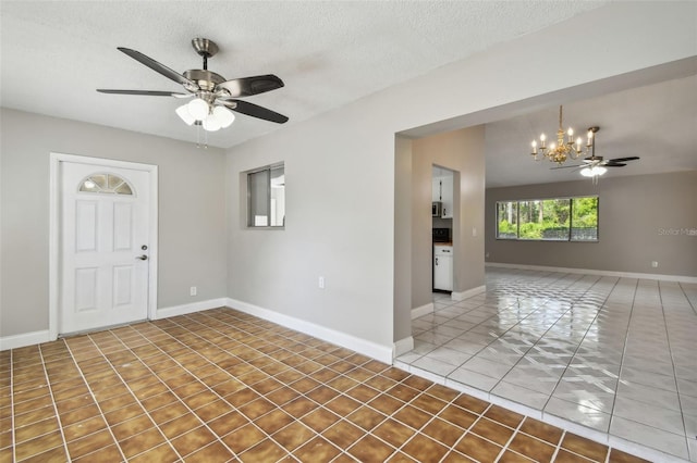 empty room featuring ceiling fan with notable chandelier and a textured ceiling