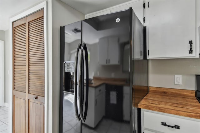 kitchen with butcher block counters, black fridge with ice dispenser, and white cabinets