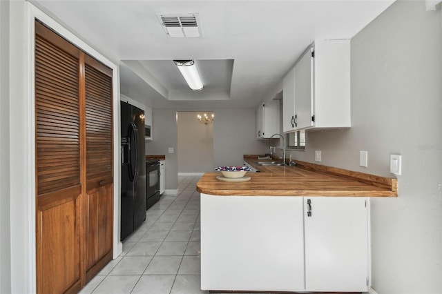 kitchen featuring sink, white cabinets, stove, light tile patterned floors, and a raised ceiling