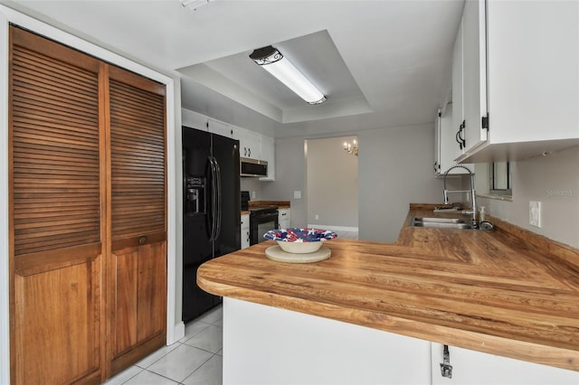 kitchen with sink, light tile patterned floors, white cabinetry, a tray ceiling, and black appliances