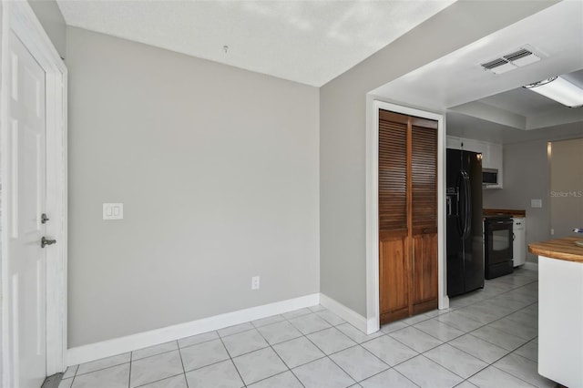 kitchen with electric stove, light tile patterned floors, and black fridge with ice dispenser