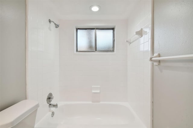 bathroom featuring tiled shower / bath and toilet